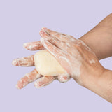 Neutriderm Brightening Bar lathered in hands, showcasing its rich foam and cleansing action. 