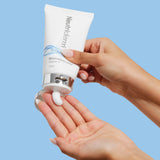 125ml Neutriderm Moisturising Lotion tube being squeezed, showing product texture in a lifestyle setting. 